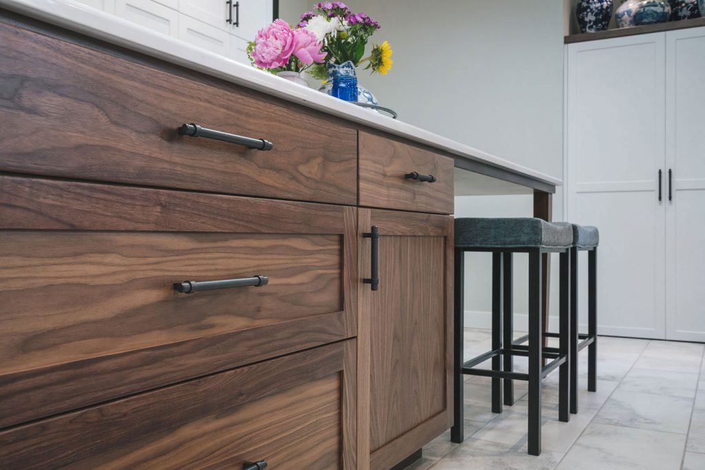 Shaker-style custom cabinetry in walnut on kitchen island, stools and white custom cabinetry in the background built by Henderer Design + Build Corvallis Oregon