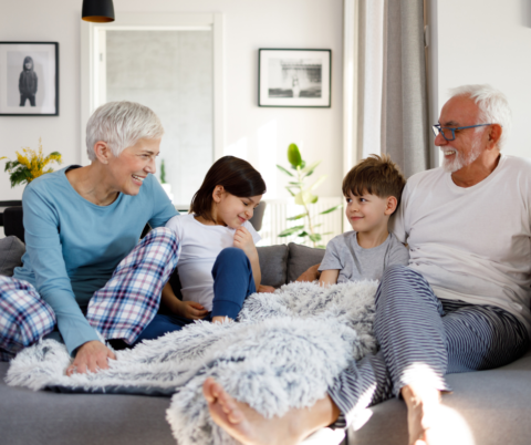 grandparents on the couch with grandchildren laughing multigenerational housing