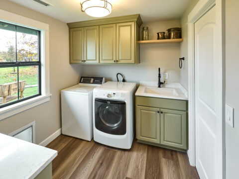 laundry room with green cabinetry and wood flooring