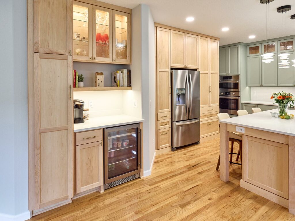 Maple custom cabinetry storage with built in fridge and wine fridge with white quartz countertop and glass cabinet faces built by Henderer Design + Build in Corvallis, Oregon