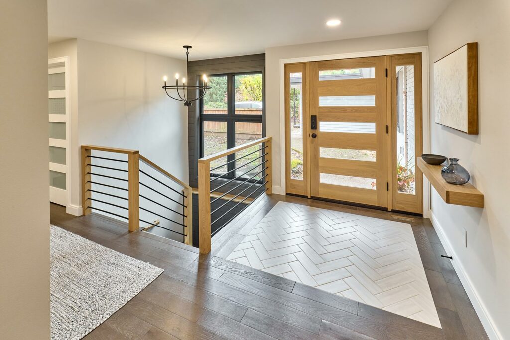 Henderer Design + Build projects Front entry with white oak entry door, tile floor inlay, dark wood flooring and iron banister to lower level